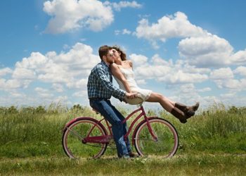 Young couple riding a bicycle while kissing
