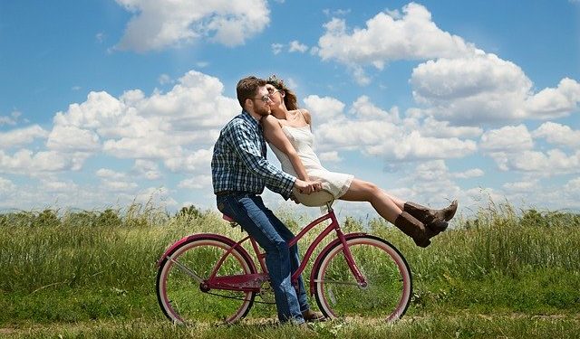 Young couple riding a bicycle while kissing