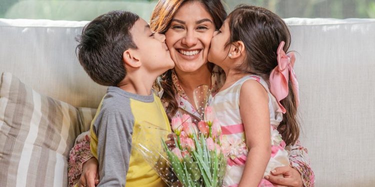 Two children giving their mother affectionate kisses on Mother's Day